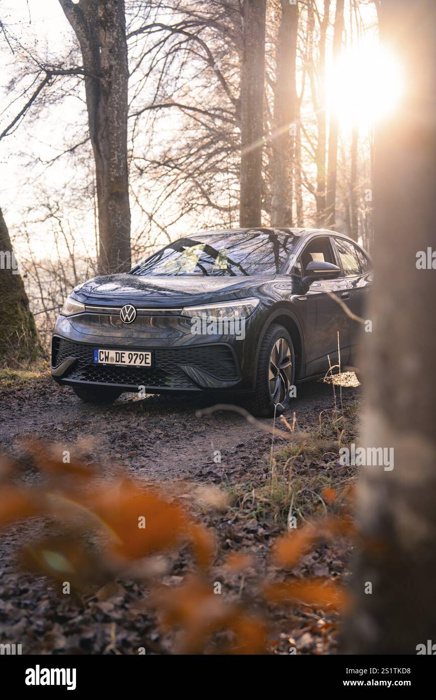 Auto parkt auf einem Waldweg, beleuchtet von niedriger Sonne, Car Sharing, Elektroauto, Volkswagen ID 5, Gechingen, Region Hecken und Gaeu, Schwarzwald, Keim Stockfoto
