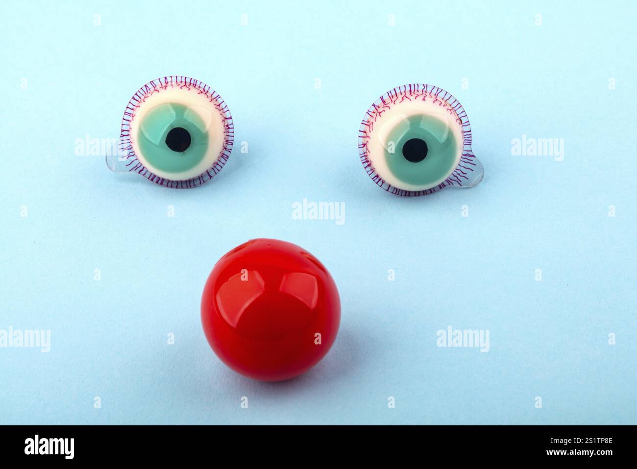 Dekorative Augen mit roter Nase auf hellblauem Hintergrund. Konzeptionelles Foto für lustige Festthemen Stockfoto