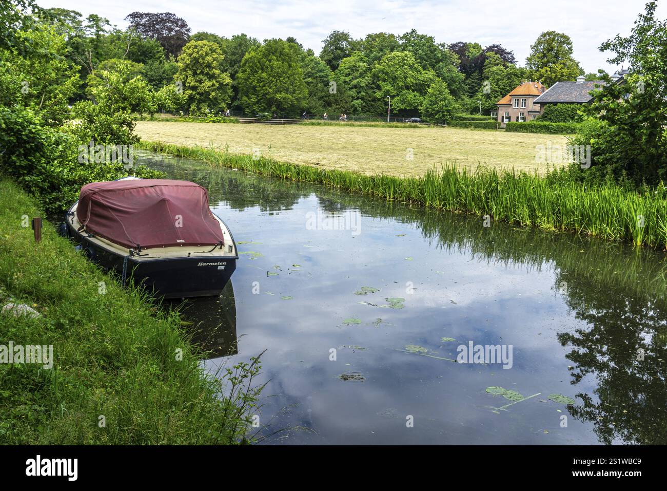 Am Kanal in den Niederlanden mit einem Boot in grüner Natur und im Sommer Stockfoto