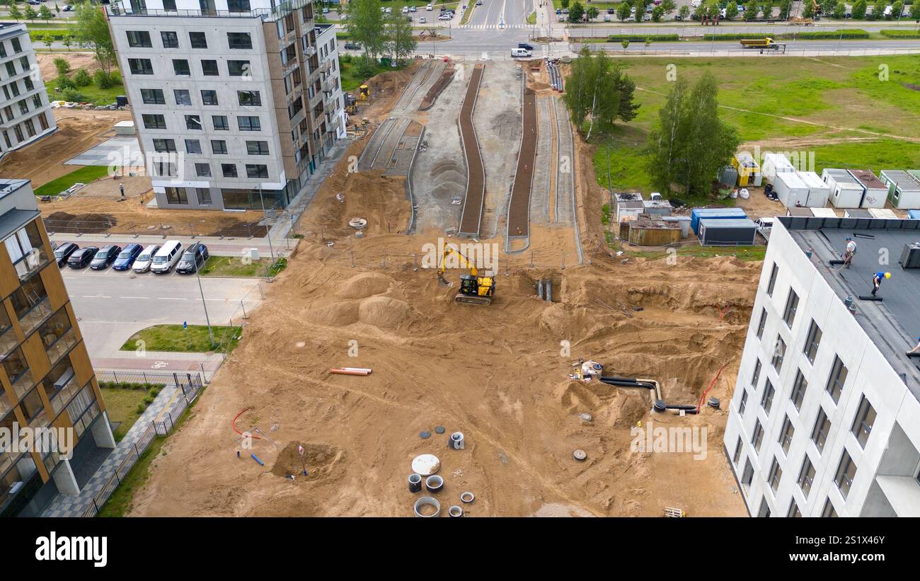 Luftaufnahme einer Baustelle mit schweren Maschinen und teilweise bebauten Straßen. Stockfoto