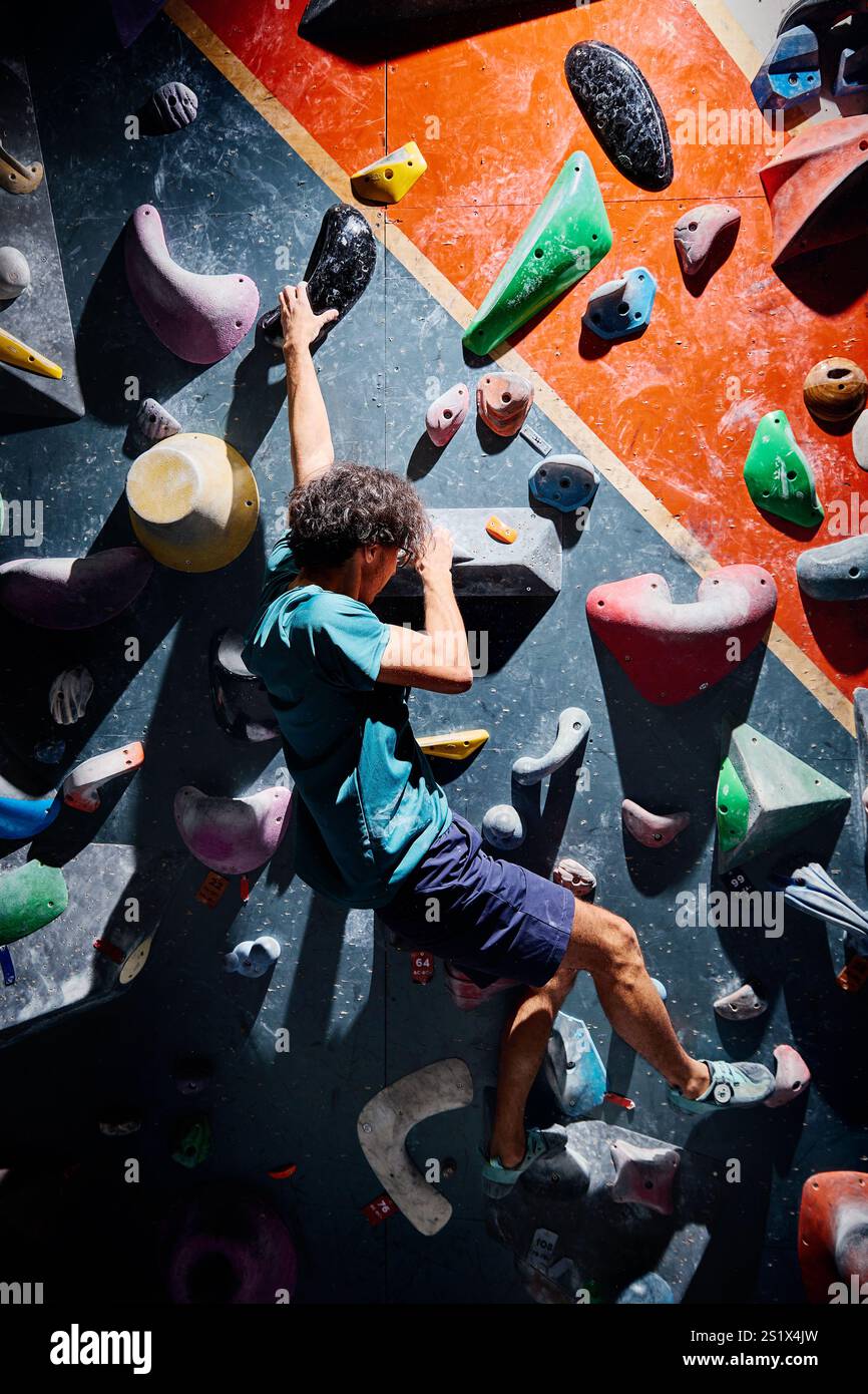 Klettersportler, der sich in der Kletterhalle drinnen an einer steilen Wand aufbewegt. Extremsport und Boulderkonzept Stockfoto