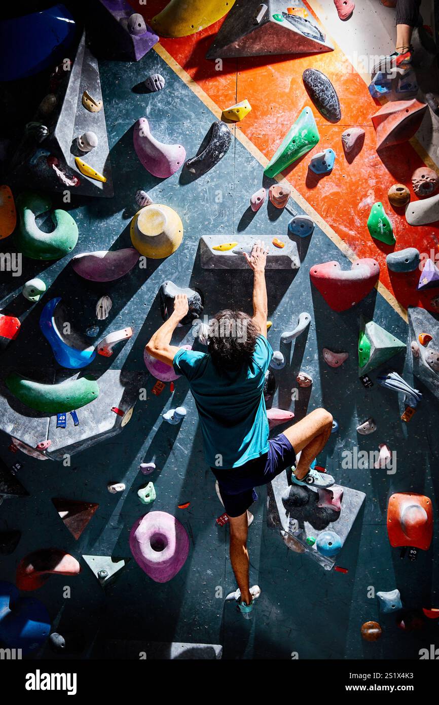 Klettersportler, der sich in der Kletterhalle drinnen an einer steilen Wand aufbewegt. Extremsport und Boulderkonzept Stockfoto