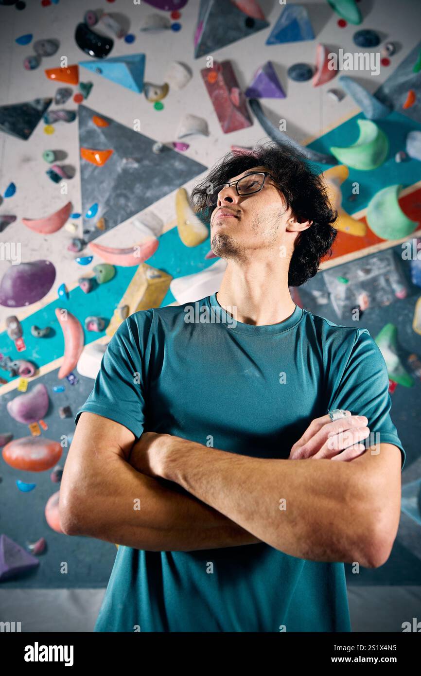 Sportlersportler Kletterporträt vor steiler Wand in Kletterhalle drinnen. Extremsport und Boulderkonzept Stockfoto
