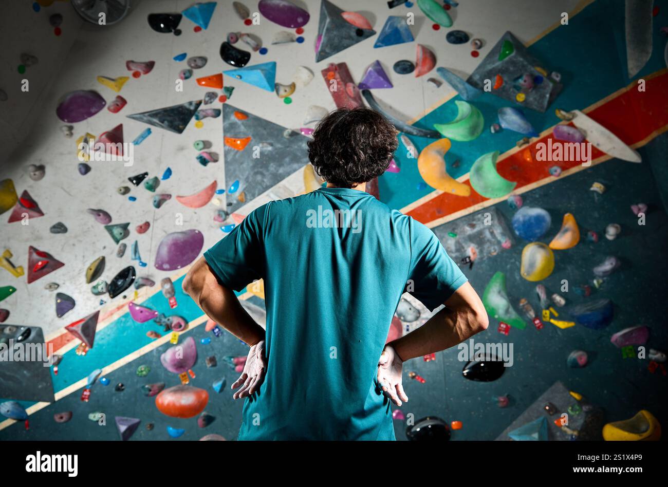 Sportler Sportler Kletterer stehen in der Kletterhalle im Innenbereich gegen die steile Wand. Extremsport und Boulderkonzept Stockfoto