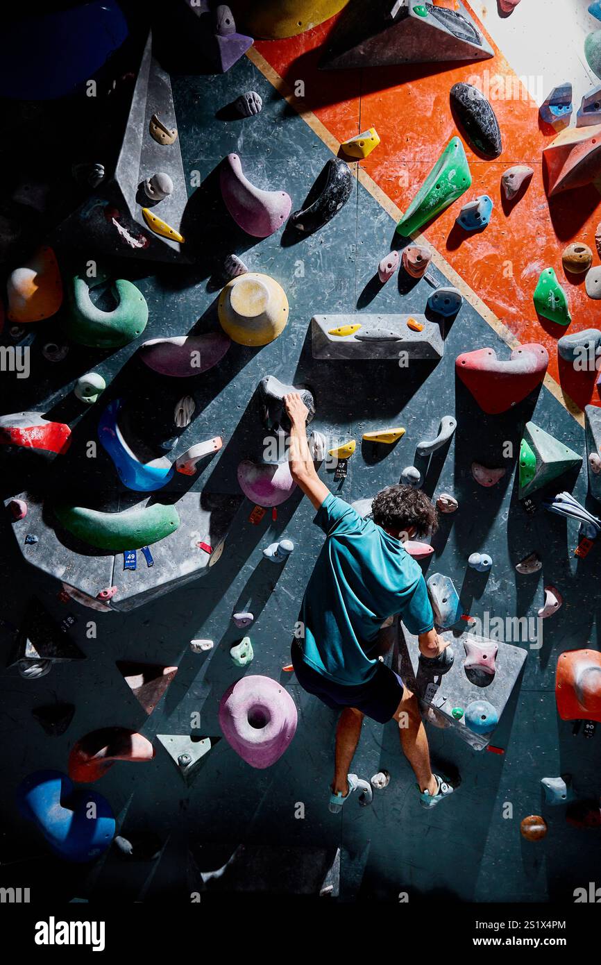 Klettersportler, der sich in der Kletterhalle drinnen an einer steilen Wand aufbewegt. Extremsport und Boulderkonzept Stockfoto