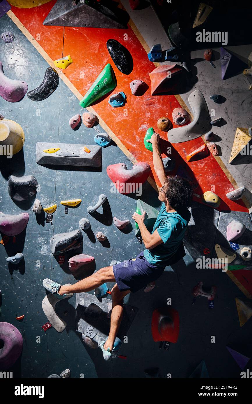 Klettersportler, der sich in der Kletterhalle drinnen an einer steilen Wand aufbewegt. Extremsport und Boulderkonzept Stockfoto