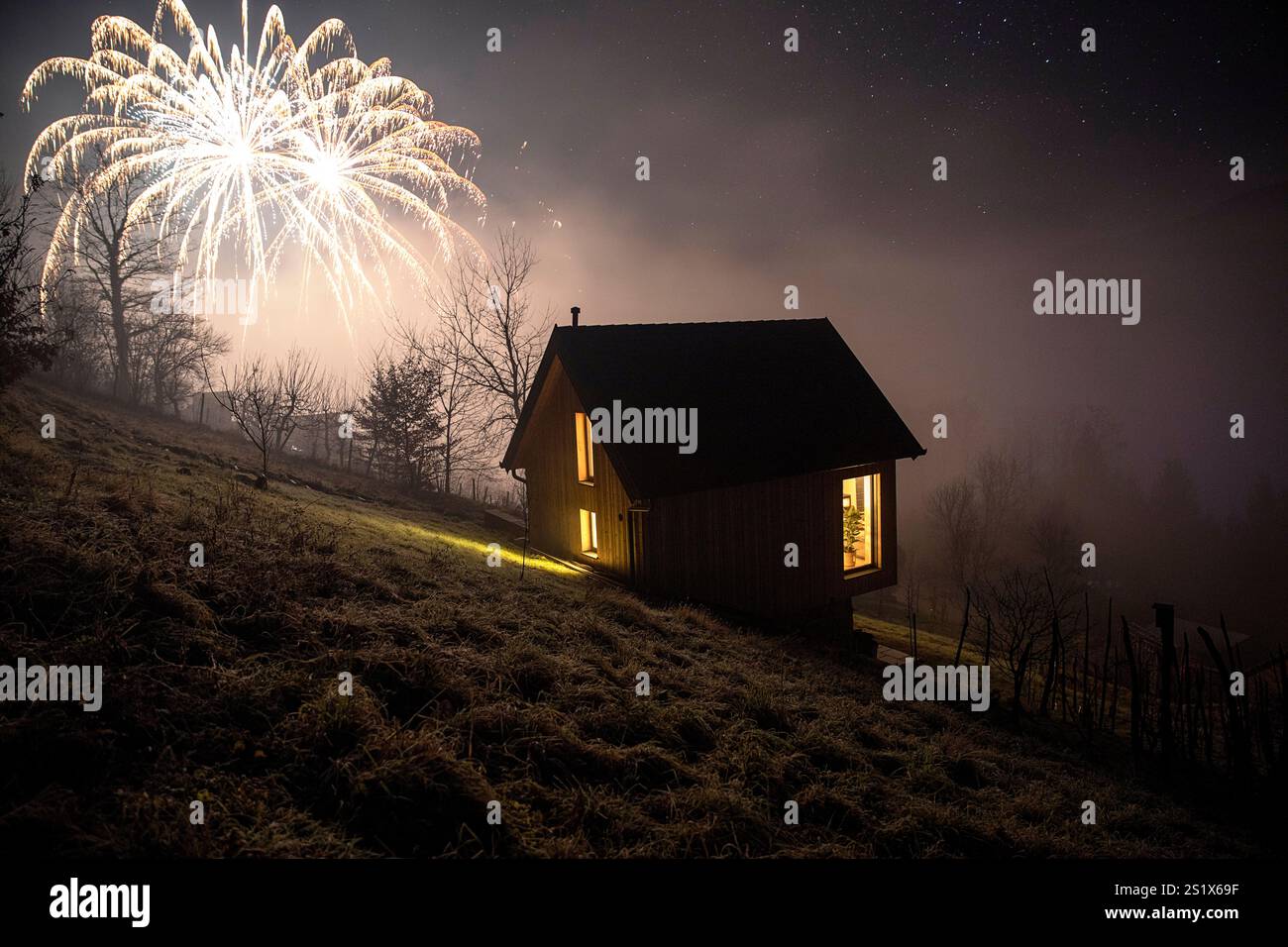 Wunderschönes hölzernes Weinberghaus in der Nacht mit Lichtern an und Neujahrsfeuerwerk auf der Rückseite in der Nähe des Kurorts dolenjske toplice, Slowenien Stockfoto