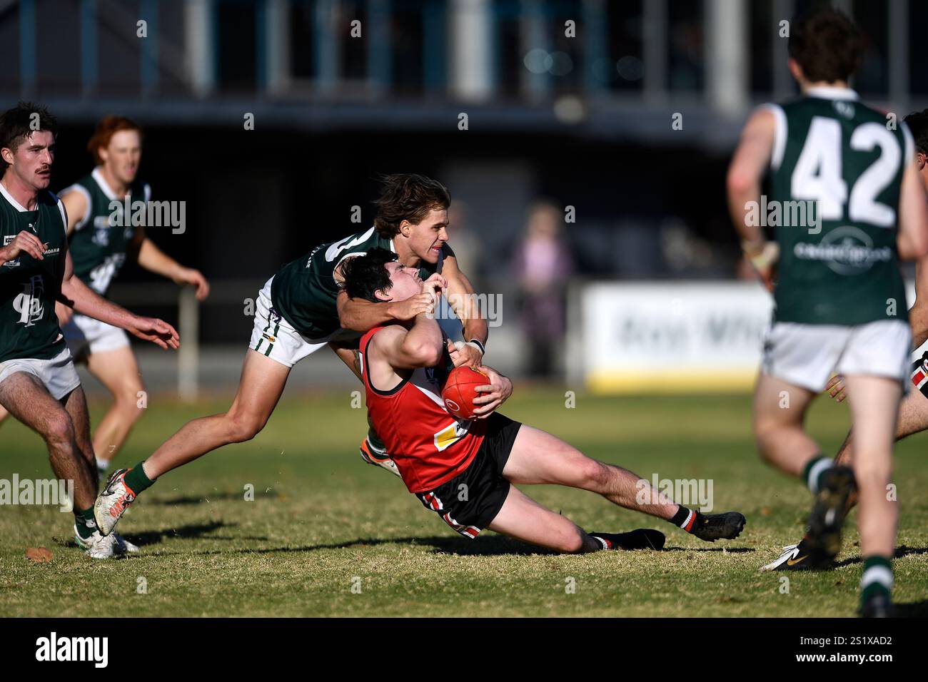 Gefährliches Tackle im Australian Rules Football. Ein Fußballspieler mit dem Arm um den Hals des Gegners tritt im australischen Fußballspiel um den Ball an Stockfoto