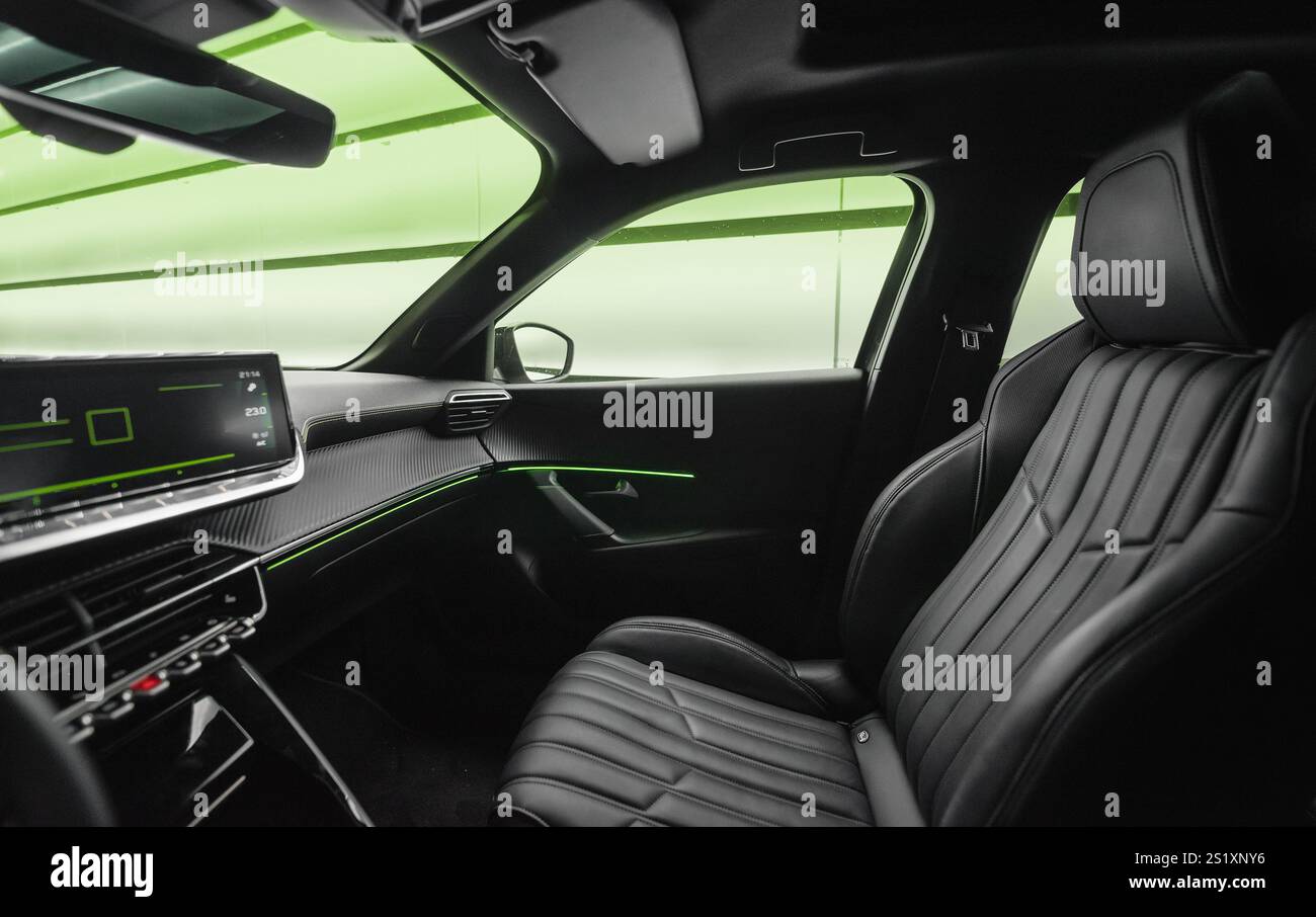Beifahrersitz im modernen Auto. Weitwinkelansicht im Cockpit des Fahrzeugs vom Fahrersitz: Mittelkonsole mit Display, Beifahrersitz und Tür aus Leder. Stockfoto