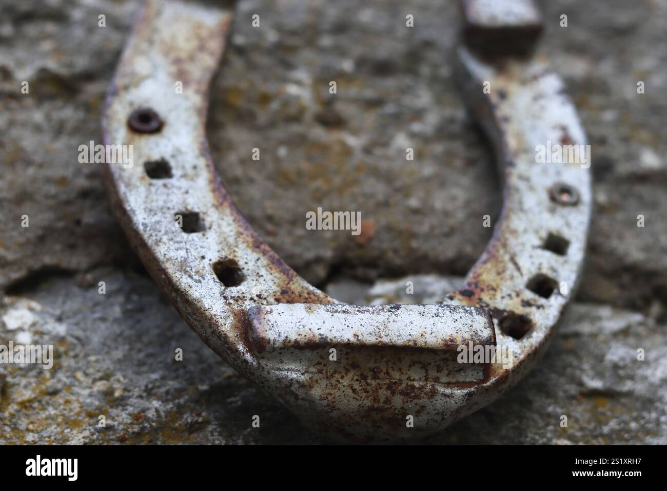 Nahaufnahme eines alten grauen, rostigen Hufeisens, das an der Steinmauer hängt. Antike Rostpferdestifte auf der Betonstruktur mit Rissen und Zementflecken. Sy Stockfoto