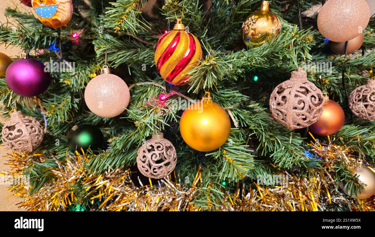 Weihnachtsbaum dekoriert mit verschiedenen schönen Kugeln, heller farbenfroher Feiertagshintergrund Stockfoto