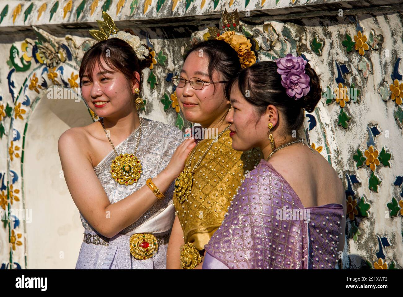 Menschen in traditioneller thailändischer Kleidung feiern den Makha Bucha Day im Wat Arun und zeigen kulturelle Schönheit und Einheit in einer spirituellen und festlichen Atmosphäre. Stockfoto