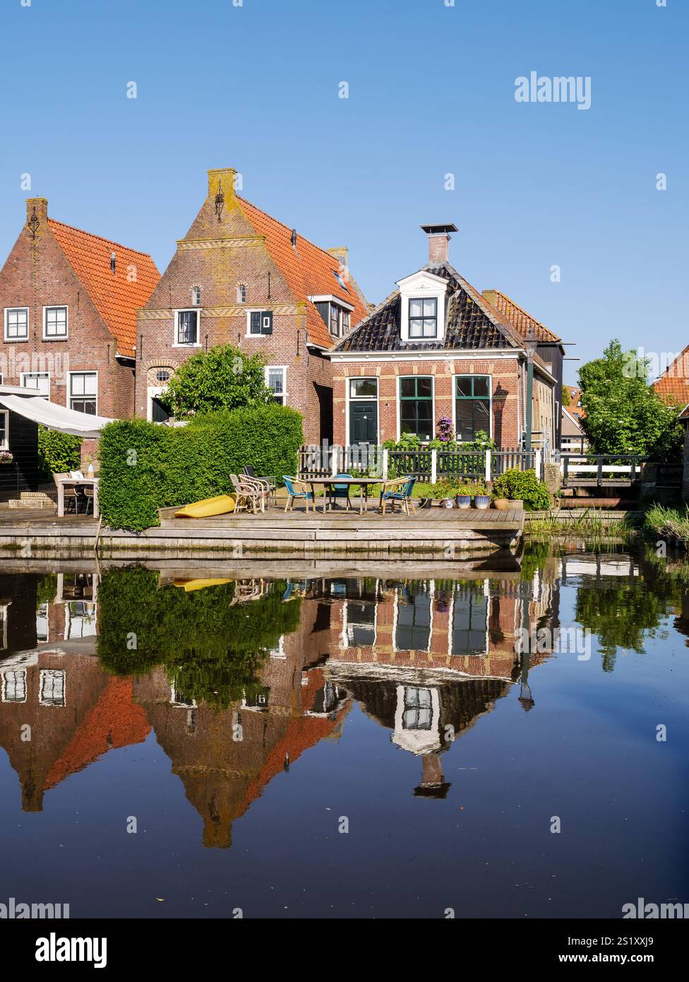 Häuser am Ufer des Zijlroede-Kanals spiegeln sich im Wasser an wolkenlosen sonnigen Tagen, Hindeloopen, Friesland, Niederlande Stockfoto