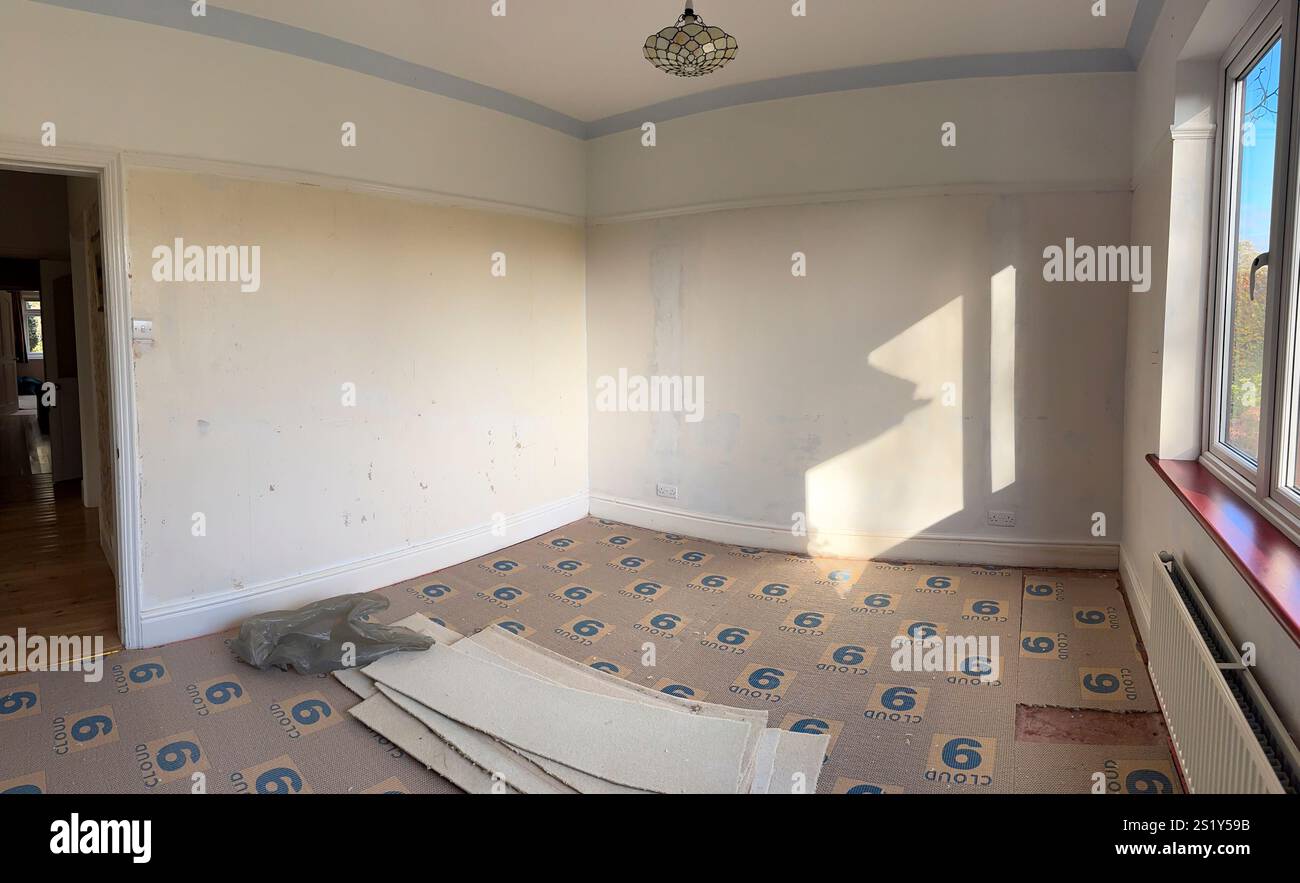 Die Tapete wurde von einer Schlafzimmerwand mit abgeschnittenem Teppich und Unterlage abgerissen, England Stockfoto
