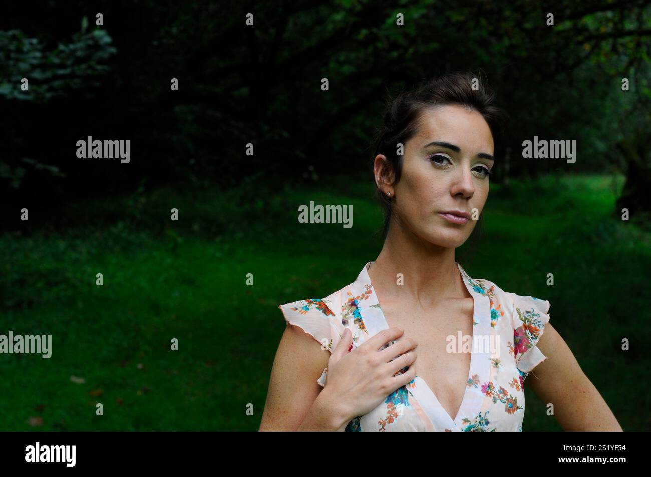 Wunderschöne junge Brünette, die draußen in einem ländlichen Waldgebiet ein Sommerkleid trägt Stockfoto