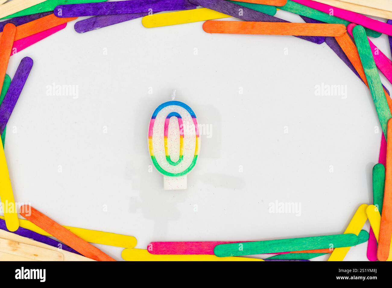 Null numerische Zahlen Form Regenbogenfarben Kerze in einem bunten hölzernen Sticks Rahmen auf weißem Hintergrund mit leerem Platz für Ihren Text. Stockfoto
