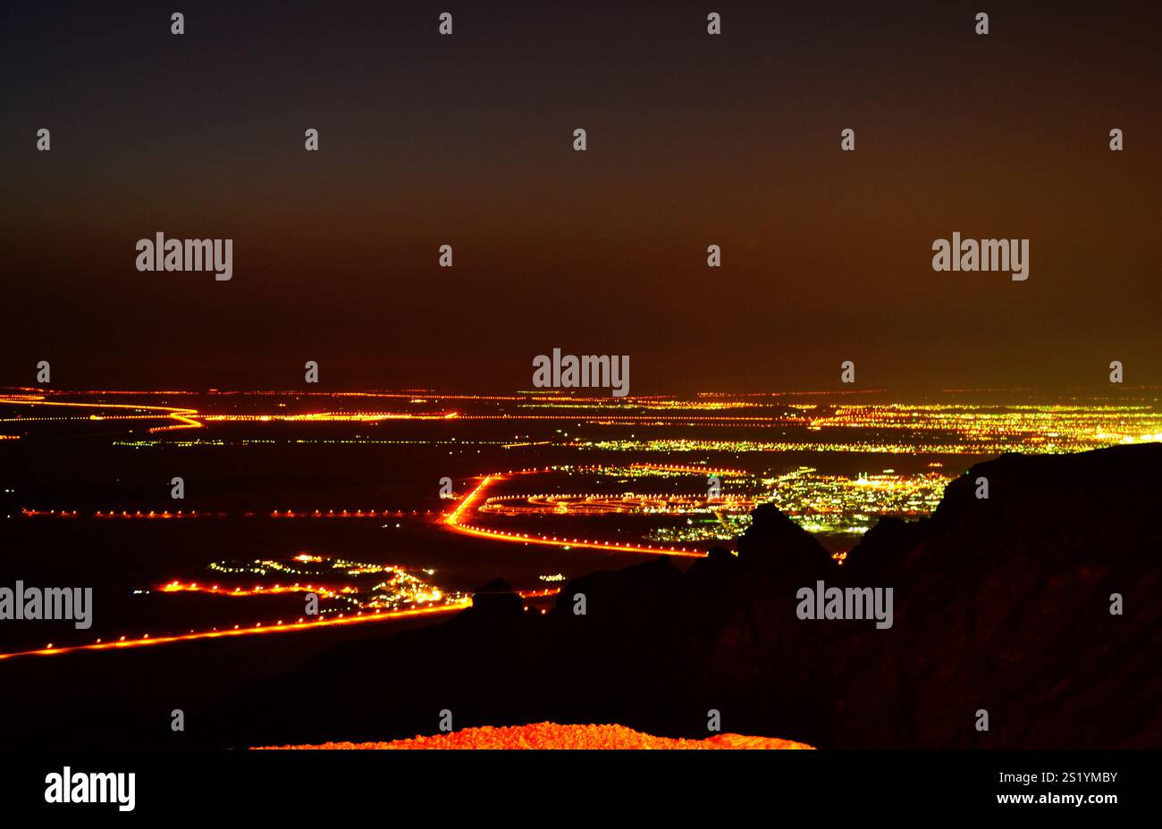 Ein ruhiger Nachtblick von Jebel Hafeet mit Stadtlichtern und Sternenhimmel. Stockfoto
