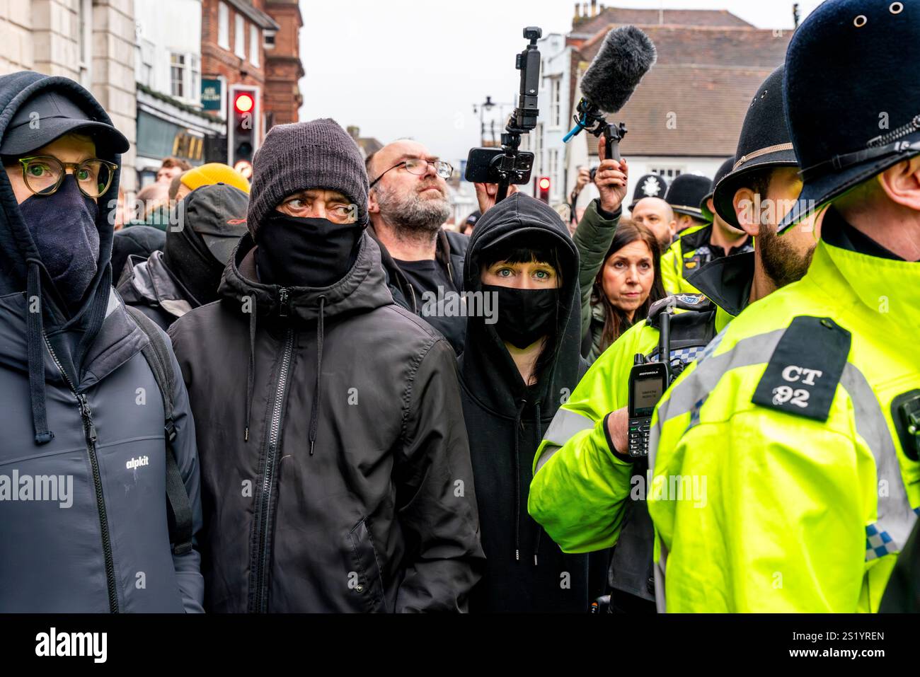 Eine Gruppe maskierter Anti-Hunt-Demonstranten, die hinter Einer Polizeilinie bei der jährlichen Southdown and Eridge Boxing Day Hunt in Lewes, East Sussex, Großbritannien, stehen. Stockfoto