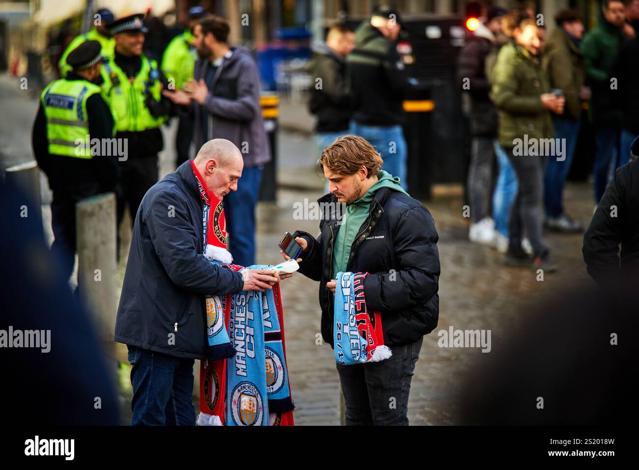 Mann, der Fußballschals an Fans im Stadtzentrum von Manchester verkauft Stockfoto
