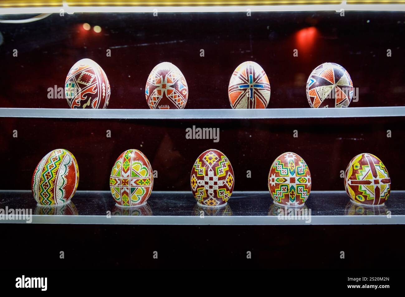 Eine Reihe farbenfroher Eier steht auf einem Regal. Die Eier sind so angeordnet, dass sie aussehen, als ob sie übereinander sitzen. Die Eier sind Stockfoto