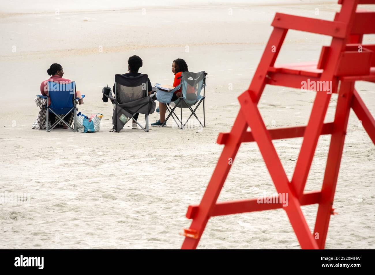 Damen, die einen ruhigen Morgen am Strand kurz nach Sonnenaufgang genießen, um Bibelstudien zu diskutieren und Gottes Schöpfung am Jacksonville Beach, FL, zu genießen. Stockfoto
