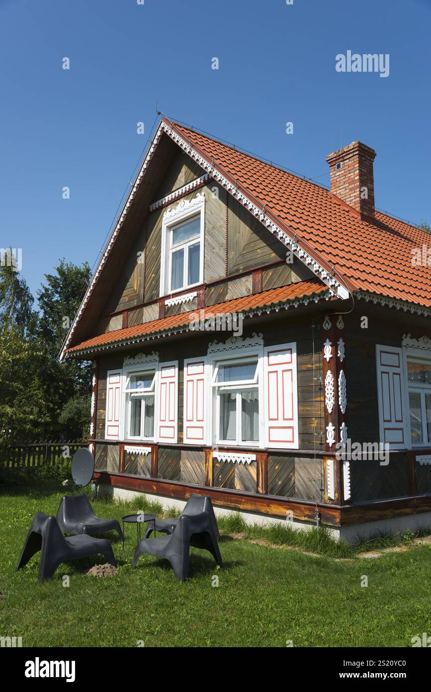 Braunes traditionelles Haus mit schwarzen Stühlen im sonnigen Garten, Budy, BiaNowieZa, Bialowieza, Woiwodschaft Podlakien, Podlakien, Polen, Europa Stockfoto