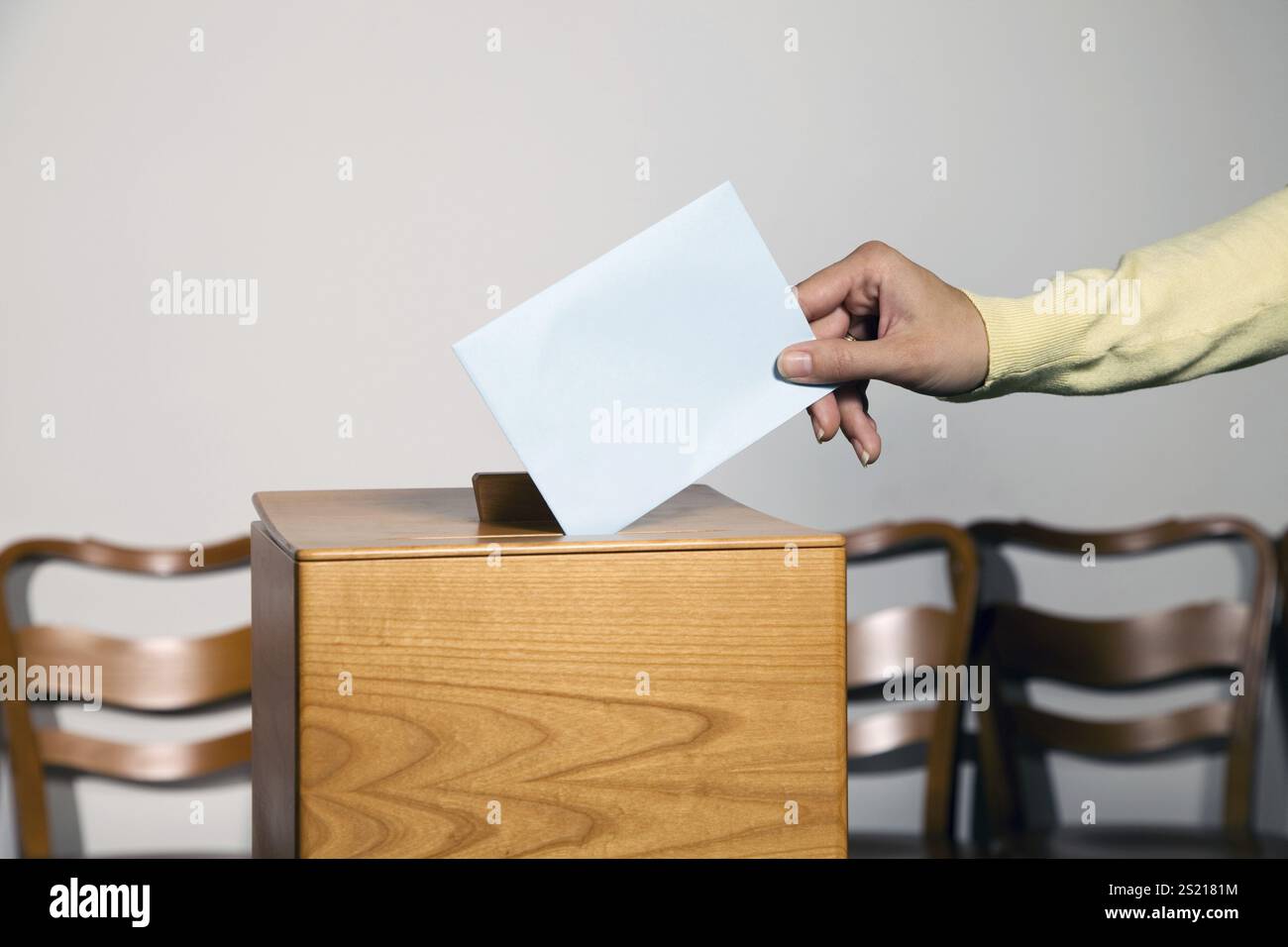 Eine junge Frau gibt ihre Stimme bei einer Wahl ab. Wahlurne am Wahllokal. Österreich Stockfoto