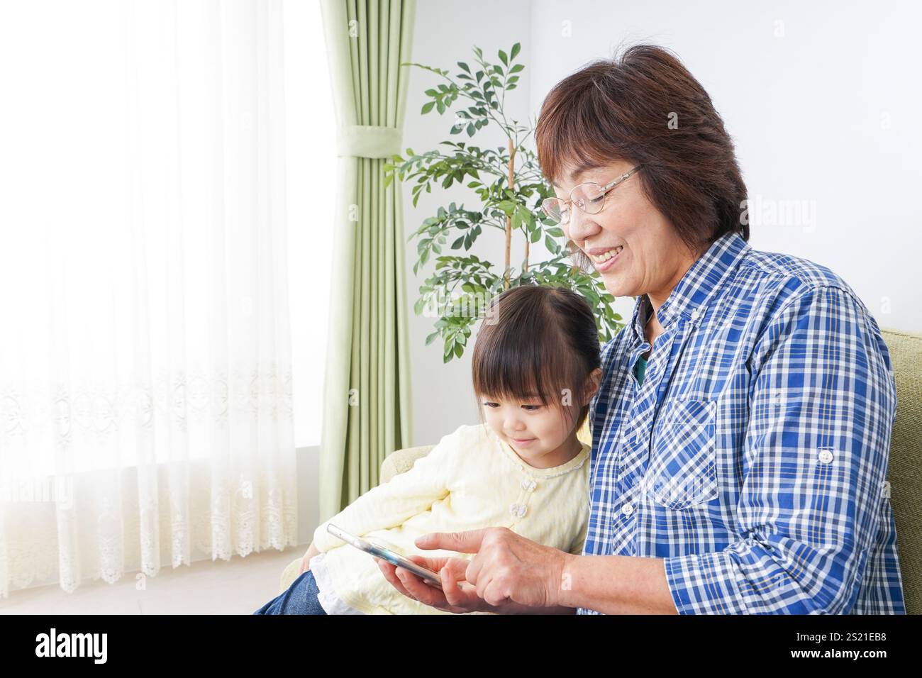Kind, das ein Telefon mit Oma benutzt Stockfoto