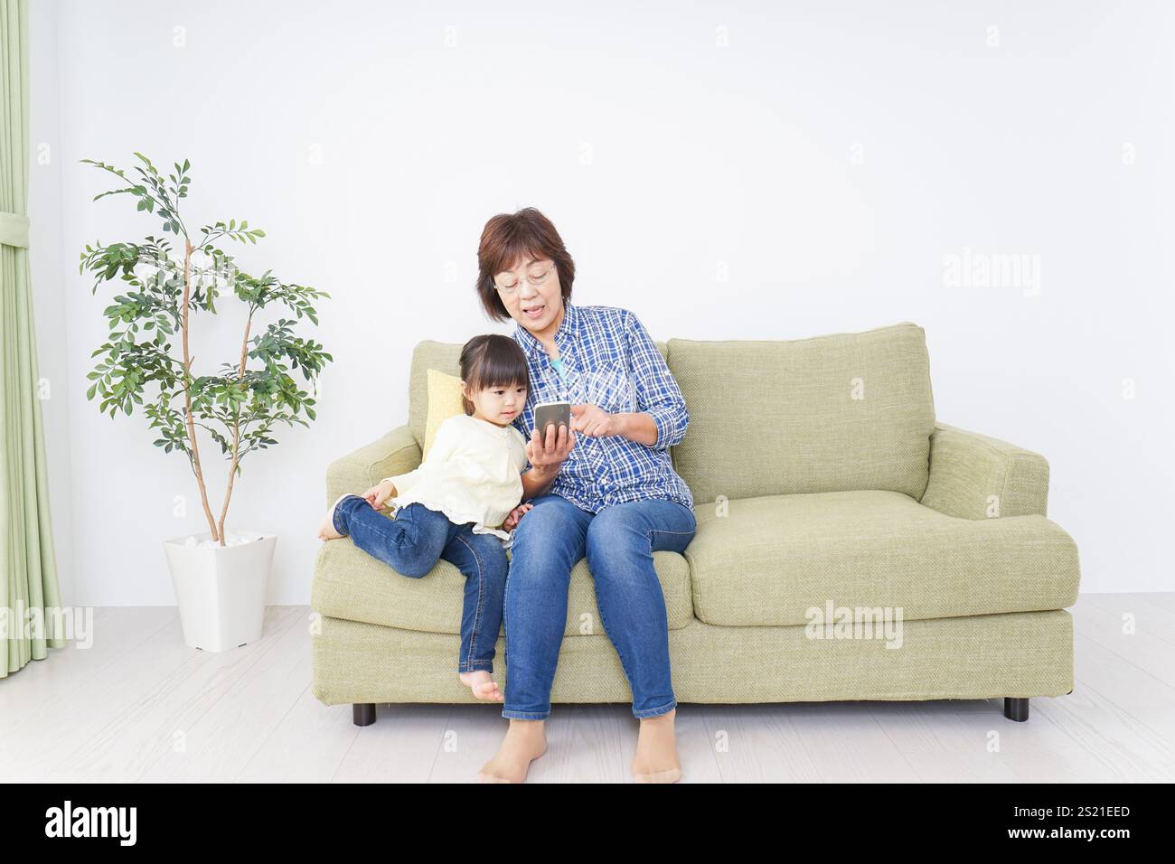 Kind, das ein Telefon mit Oma benutzt Stockfoto
