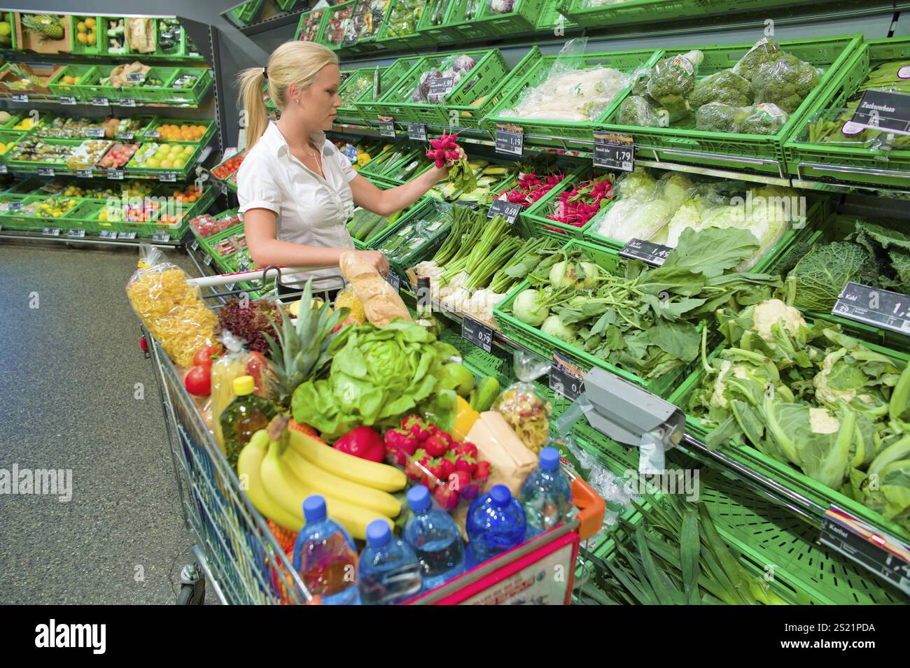 Eine junge Frau, die Obst und Gemüse in einem Supermarkt in Österreich kauft Stockfoto