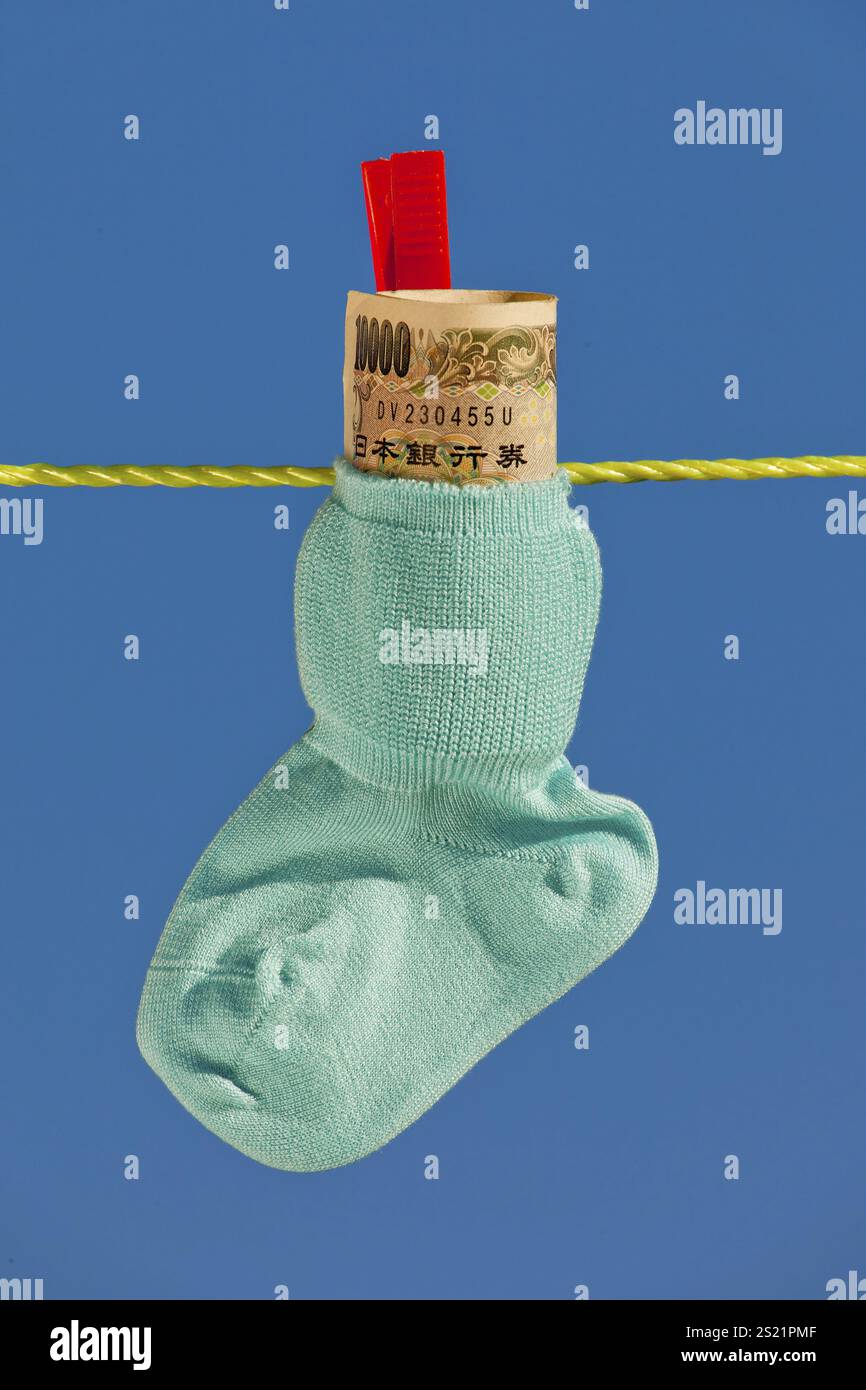 Babysocken auf der Wäscheleine mit Yen-Banknoten aus Japan. Österreich Stockfoto