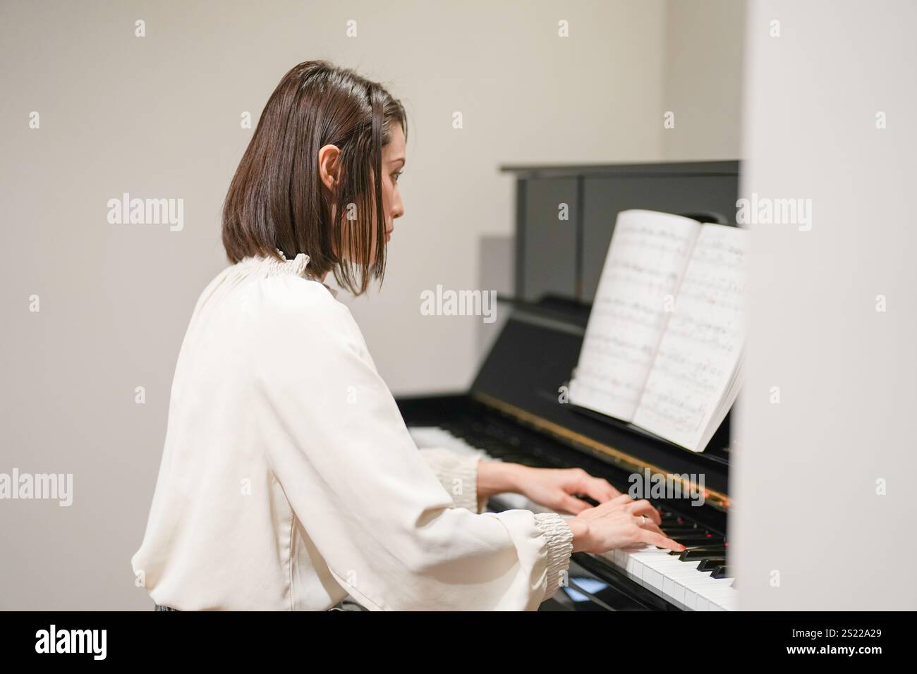 Eine Japanerin im Alter von 30 Jahren spielt zu Hause Klavier. Stockfoto
