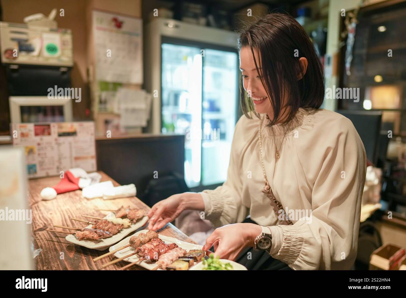 Ein japanisches Elternteil und Kind im Alter von 30 Jahren beobachten Yakitori-Gerichte in einem Izakaya. Stockfoto