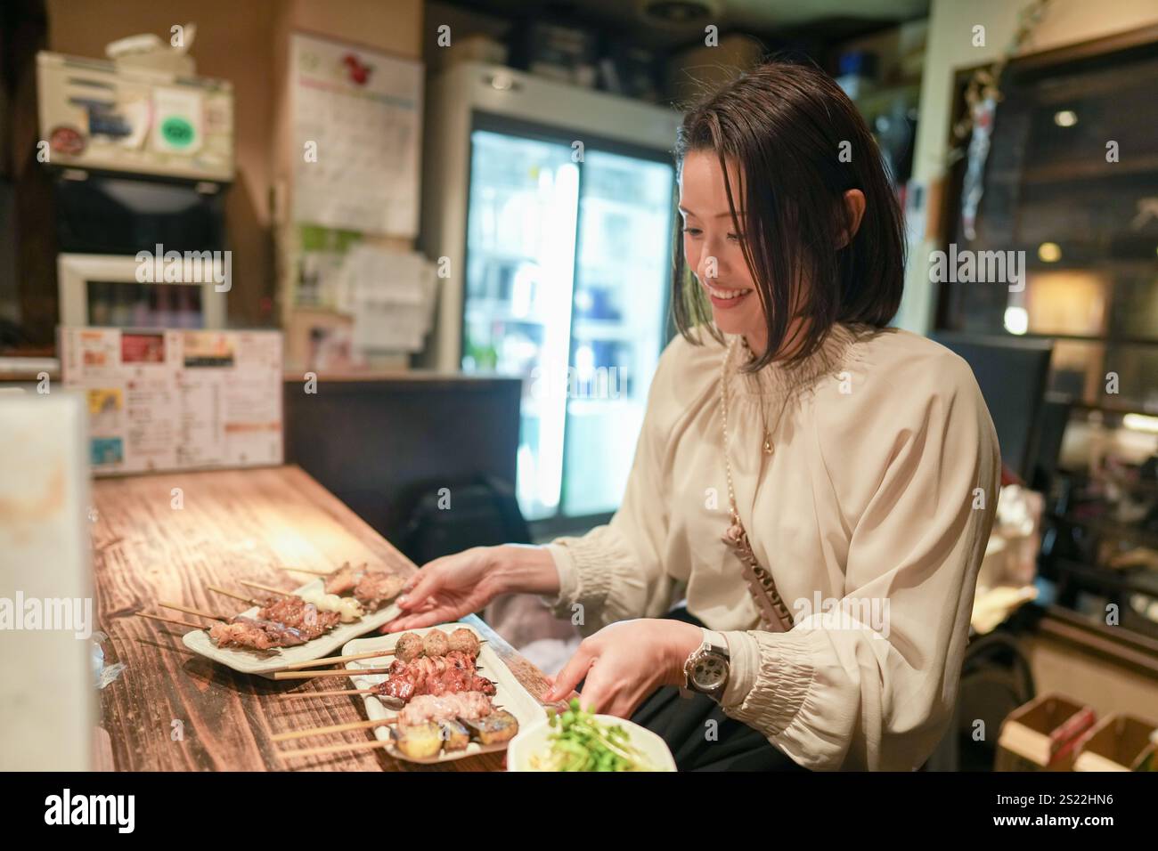 Ein japanisches Elternteil und Kind im Alter von 30 Jahren beobachten Yakitori-Gerichte in einem Izakaya. Stockfoto