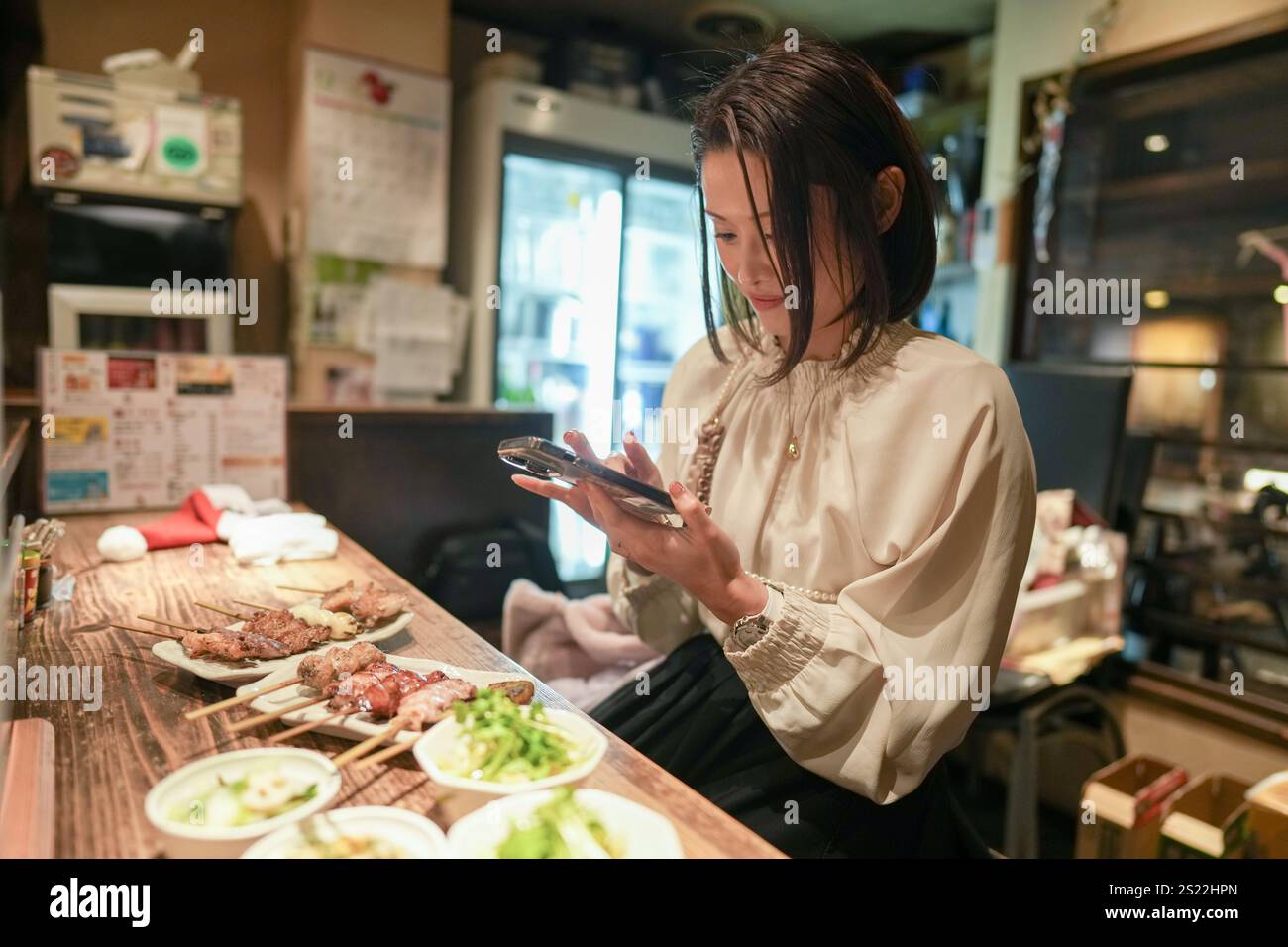 Ein japanisches Elternteil und Kind im Alter von 30 Jahren beobachten Yakitori-Gerichte in einem Izakaya. Stockfoto
