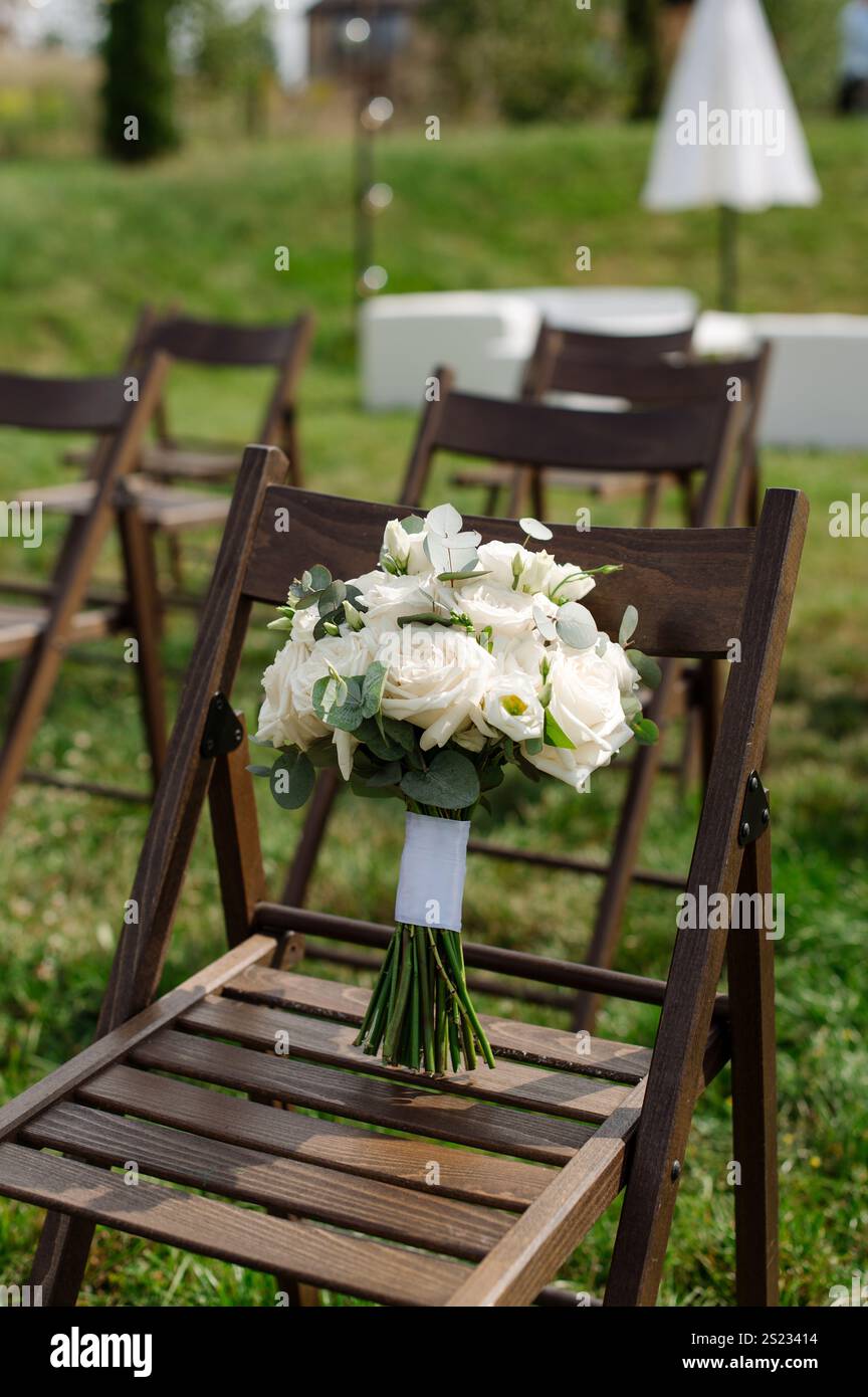 Zarter Hochzeitsstrauß auf einem Holzstuhl am Hochzeitstag Stockfoto