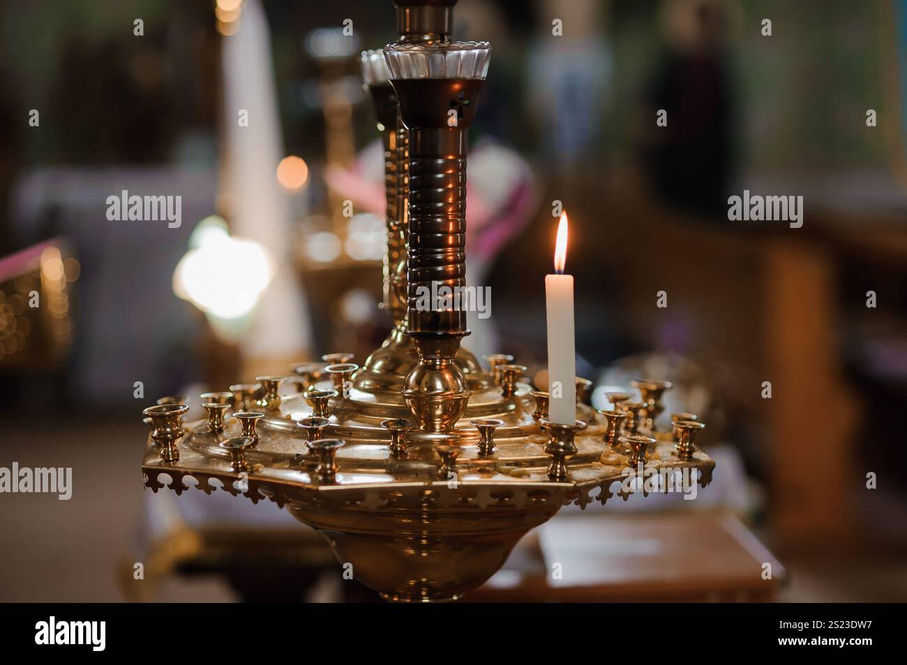 Eleganter Kerzenhalter aus Messing mit Einer einzelnen beleuchteten Kerze in einer ruhigen Umgebung. Stockfoto