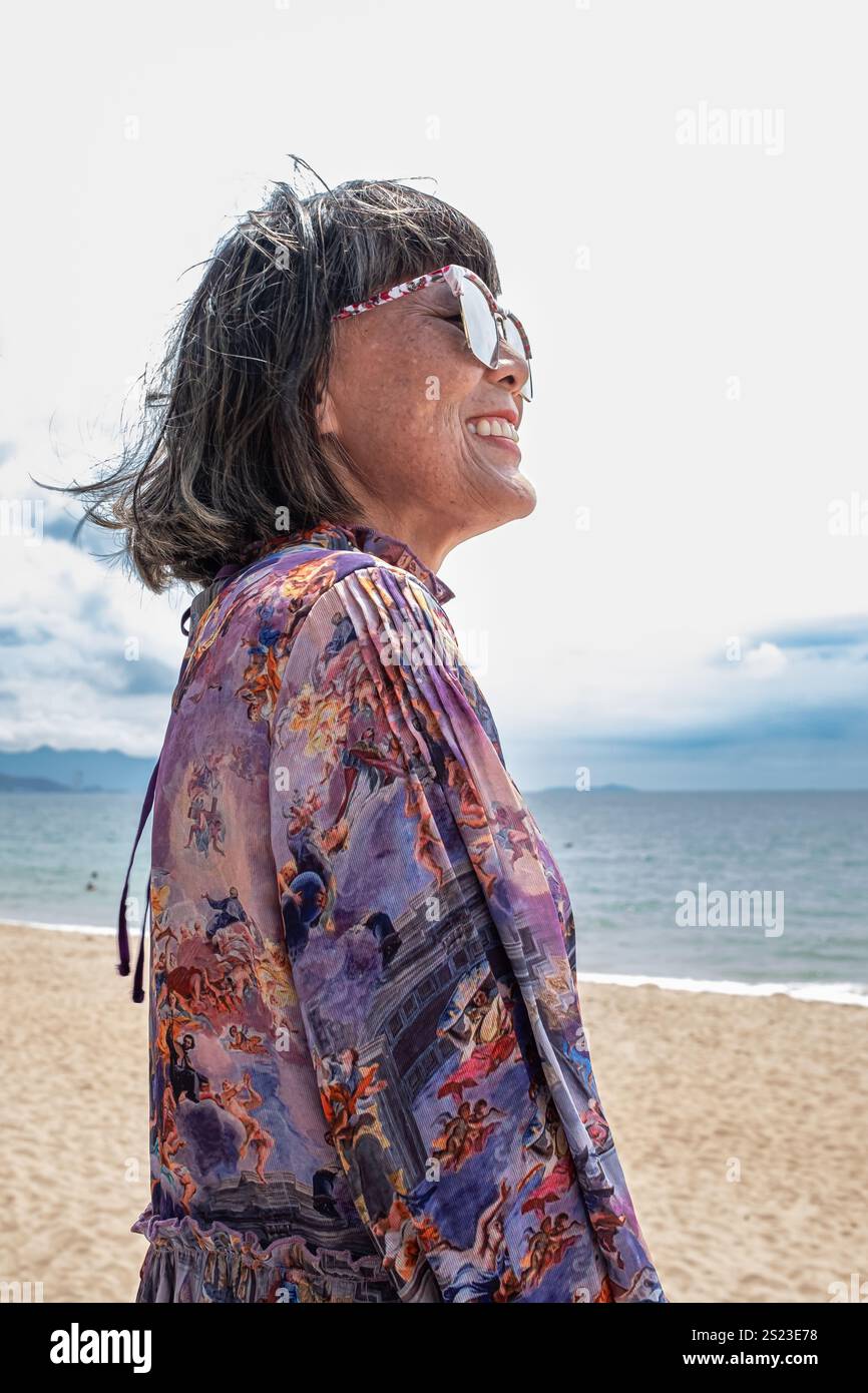 Glückliche asiatische alte Frau lächelt, fröhlich. Asiatische ältere Frau lächelt. Ältere schöne Frau graue kurze Haare trägt Sonnenbrille mit positiver Einstellung Stockfoto