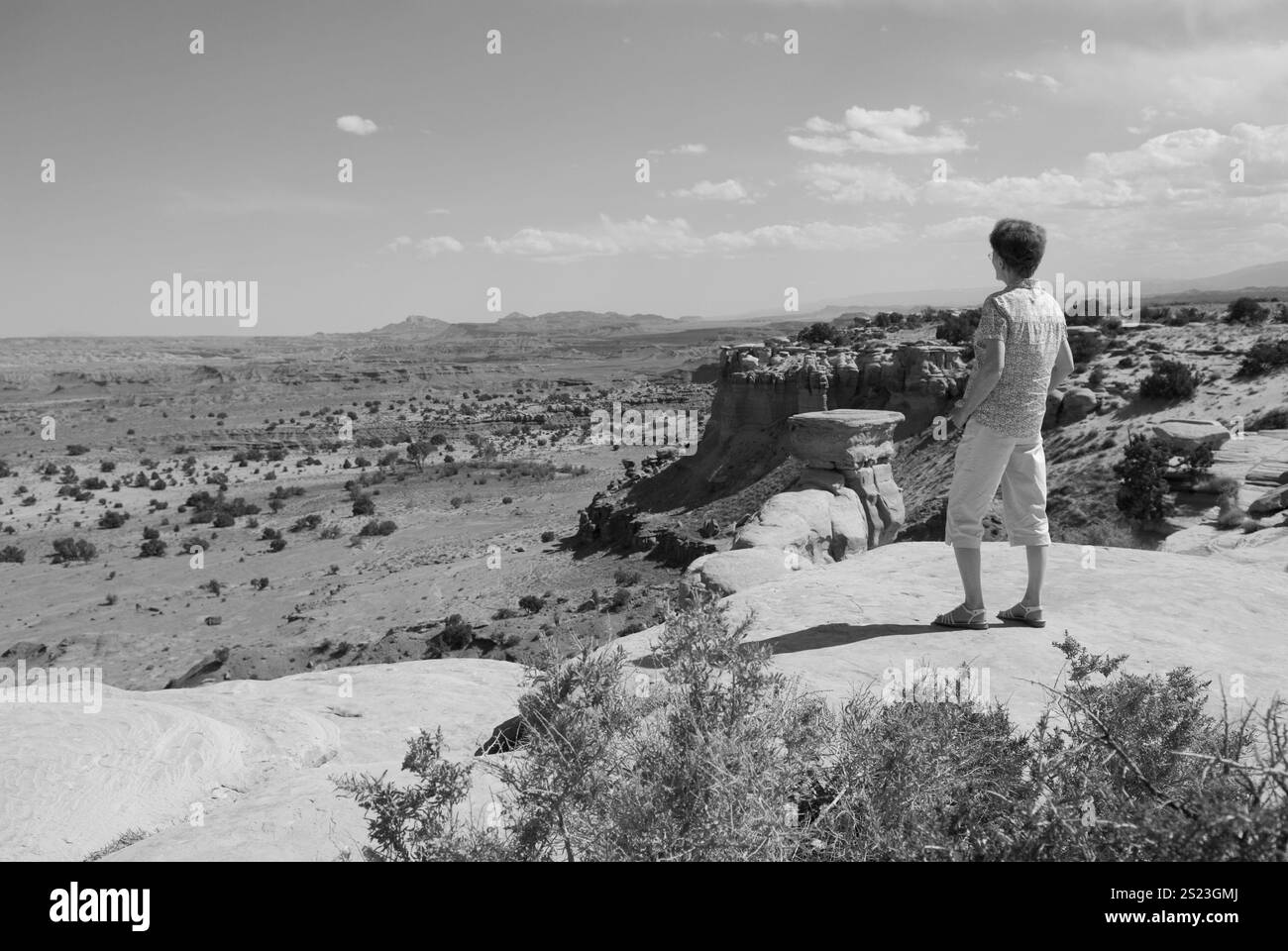 Ältere kaukasische Frau, die den atemberaubenden Blick auf den San Rafael Swell, ein beliebter malerischer Zwischenstopp in Utah, USA, bewundert. Stockfoto