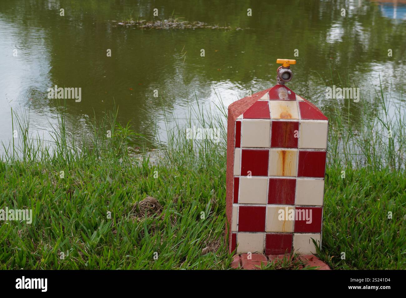 Wand mit weißen und roten Fliesen und Wasserhahn. Unscharfer Hintergrund Stockfoto