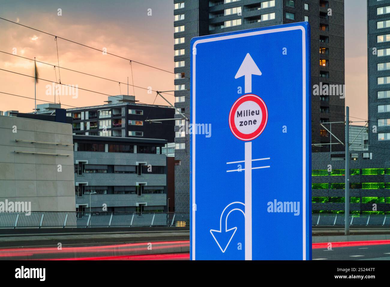 Stadtwarnschild mit niederländischem Text für „Emissionszone“ vor der Straße und Stadtgebäuden Stockfoto