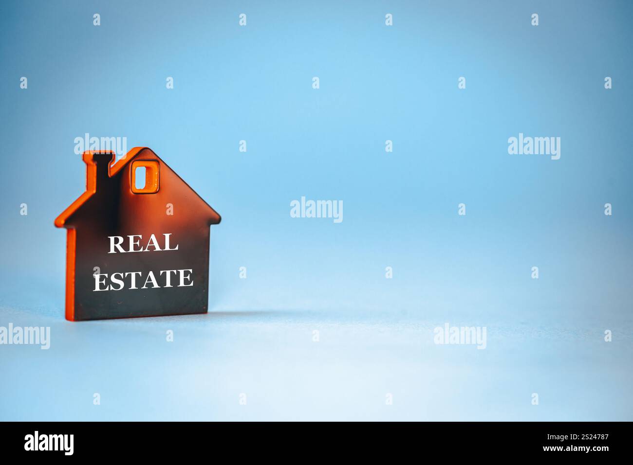 Immobiliensymbol. Hausminiatur mit den Worten Real Estate. Konzeptionelle Wörter. Immobilienmarkt. Schöner blauer Hintergrund, Kopierraum Stockfoto