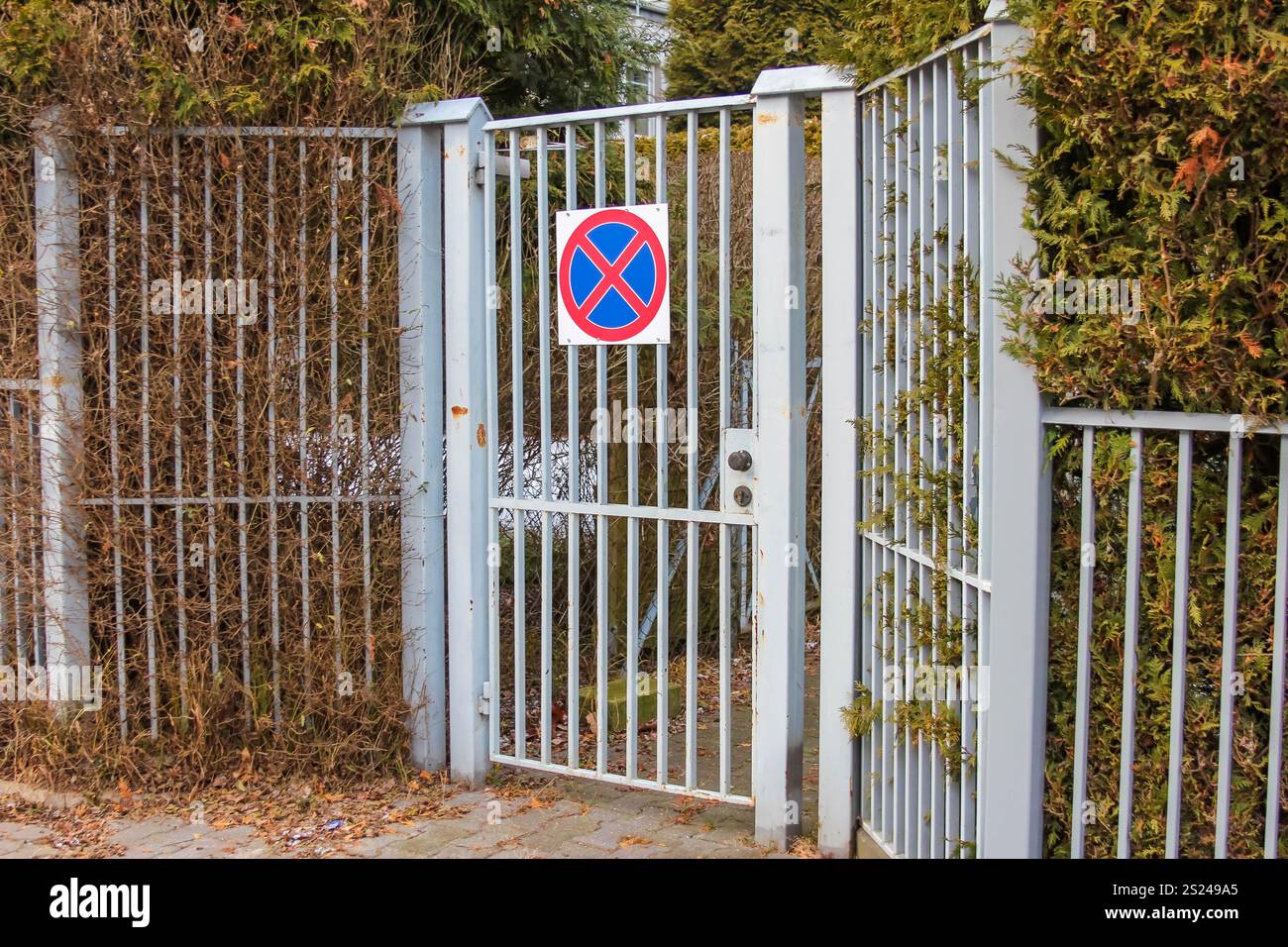 Ein Tor mit einem Schild ohne Parkplatz ist deutlich sichtbar, umgeben von Grün und Sträuchern in einer ruhigen Wohngegend. Stockfoto