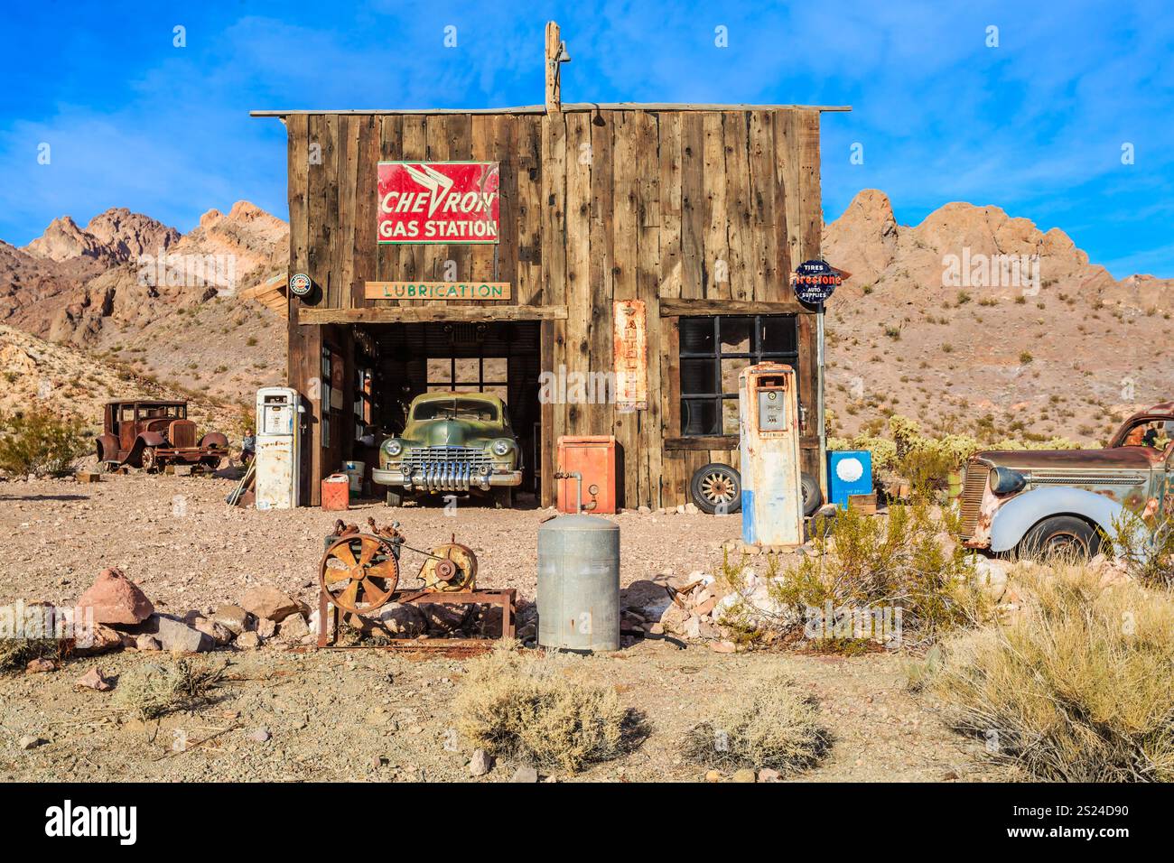 Eine Tankstelle mit einem Schild, auf dem Chevron steht. In der Garage steht ein altes Auto. Das Gebäude ist alt und rustikal Stockfoto