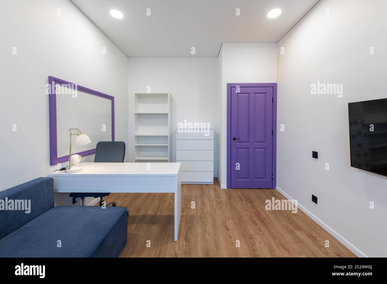 Heller und einladender Raum mit modernem Sofa, Schreibtisch, Schrank und farbenfrohen dekorativen Elementen für ein fröhliches und funktionales Ambiente. Stockfoto