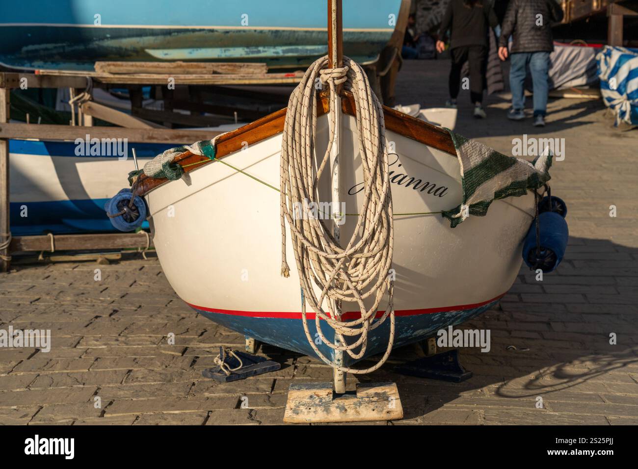 Ein Boot aus dem Wasser mit einem Maler am Bug am Hafen in Riomaggiore, Cinque Terre, Italien. Stockfoto
