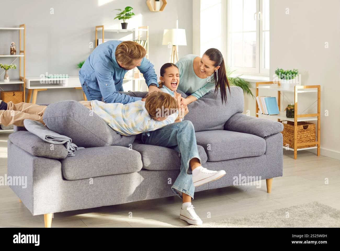 Glücklicher Familienspaß, Eltern mit zwei Kindern haben Spaß zu Hause, lachen überfröhliche Mutter und Vater Stockfoto