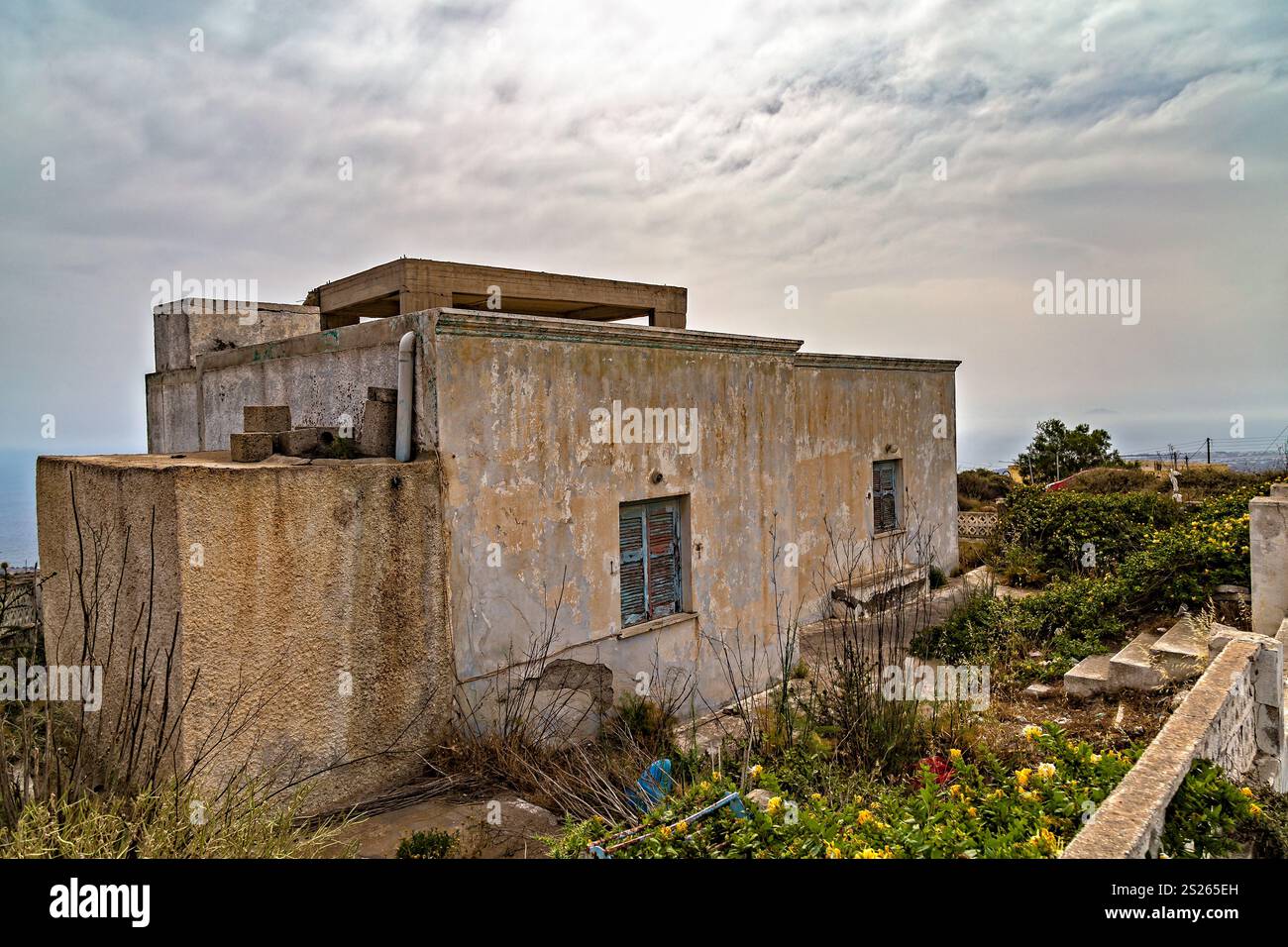 Rustikales mediterranes Haus umgeben von Natur unter bewölktem Himmel, Santorin, Griechenland Stockfoto