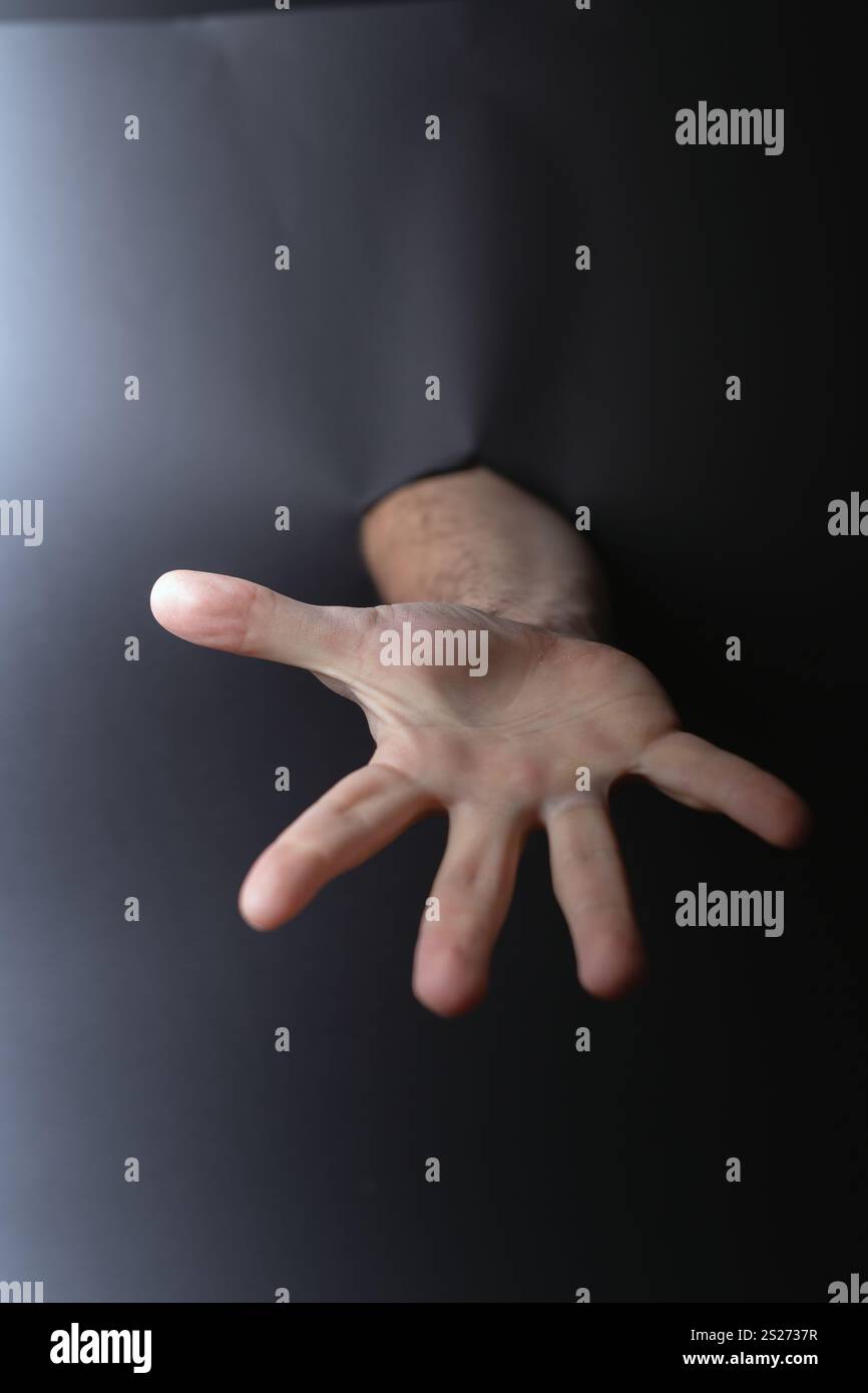 Foto-Outreach und Verbindung: Hand, die durch den dunklen Raum greift, symbolisiert den Wunsch nach Hilfe, Hilfe und Großzügigkeit in menschlicher Interaktion und Emoti Stockfoto