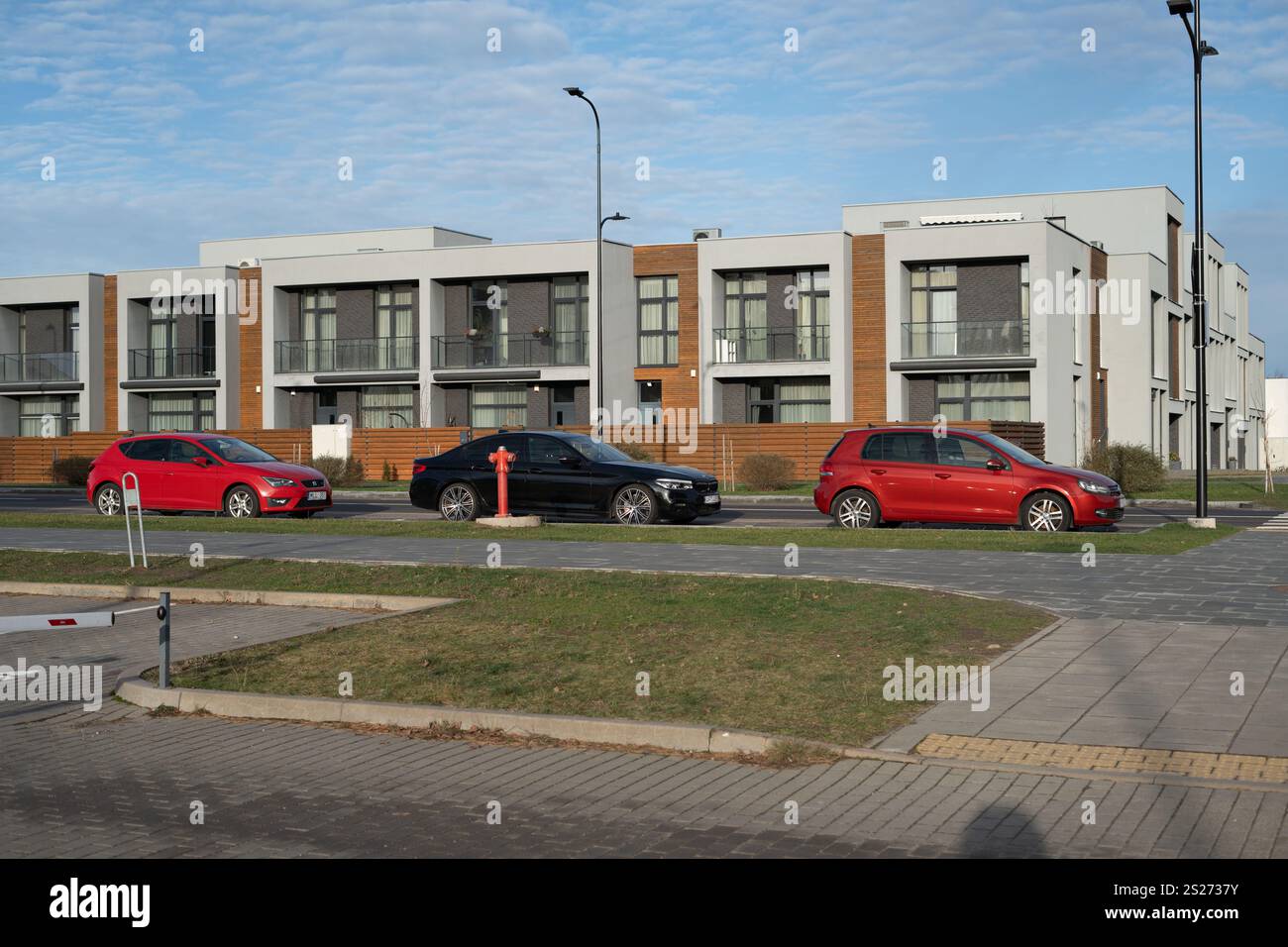 Moderner Wohnkomplex mit geparkten Autos mit zeitgenössischem architektonischem Design und urbanem Wohnumfeld in einem Vorstadtviertel Stockfoto